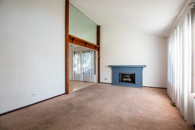 a view of an empty room with a fireplace and a window