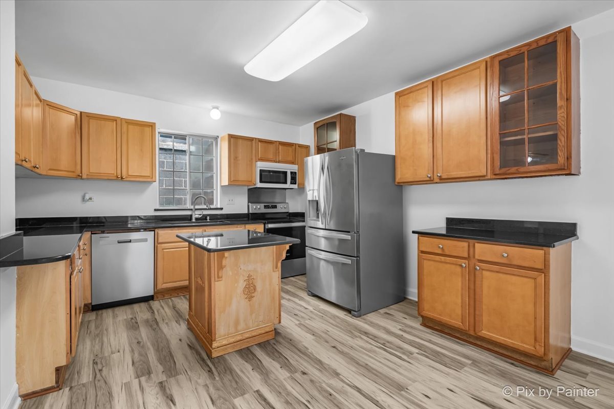309 Griswold Street Elgin, IL 60123 - Photo 12 of 39 a kitchen with stainless steel appliances granite countertop a refrigerator a stove top oven a sink and dishwasher with wooden floor