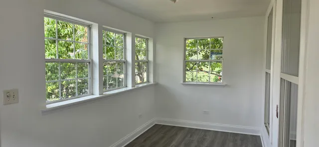 a view of an empty room with wooden floor and windows