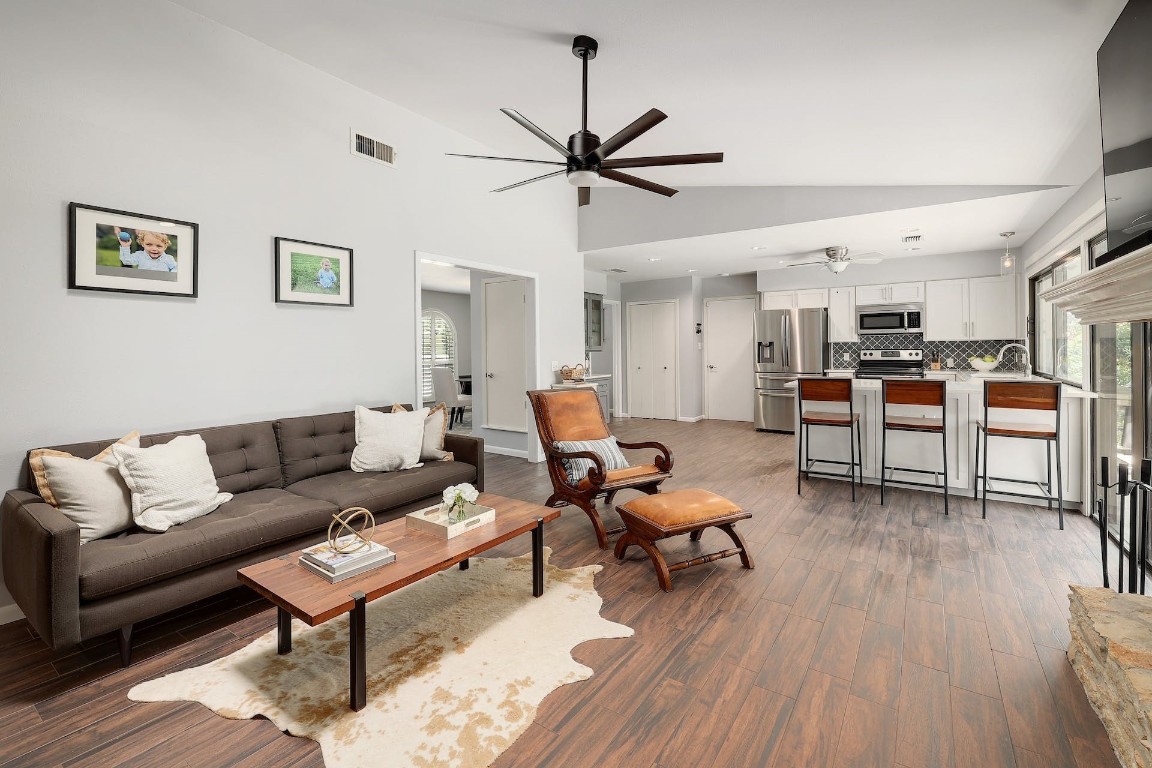 a living room with furniture kitchen view and a wooden floor