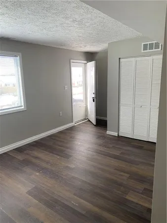 a view of an empty room with wooden floor and window