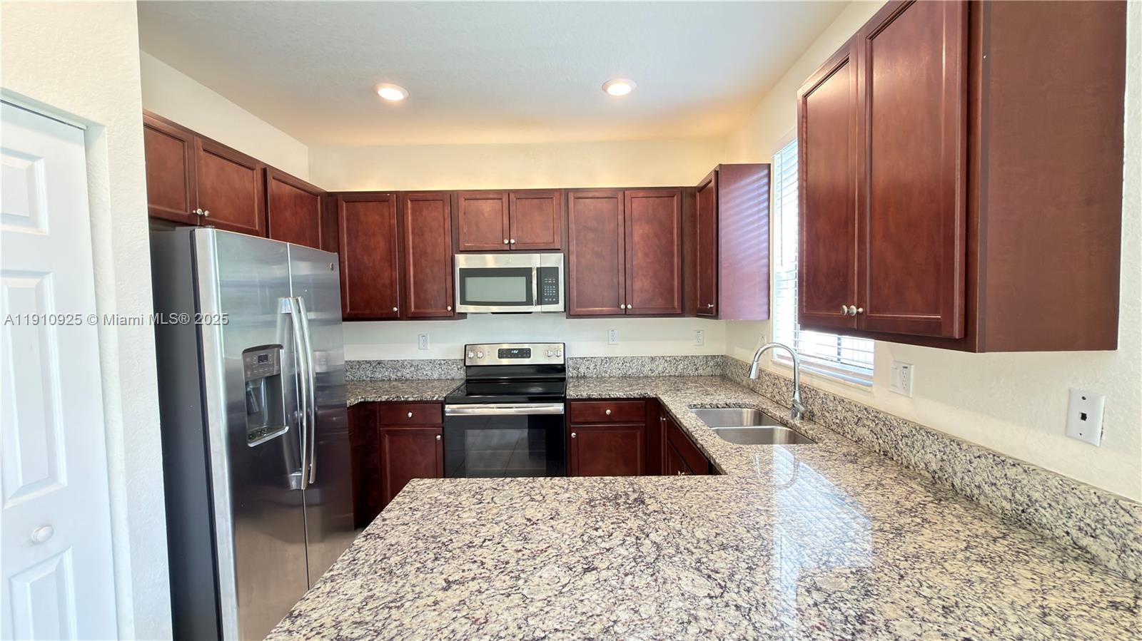 10337 West 34th Lane, Unit 10337 Hialeah, FL 33018 - Photo 15 of 50 a kitchen with stainless steel appliances granite countertop a refrigerator stove top oven and sink