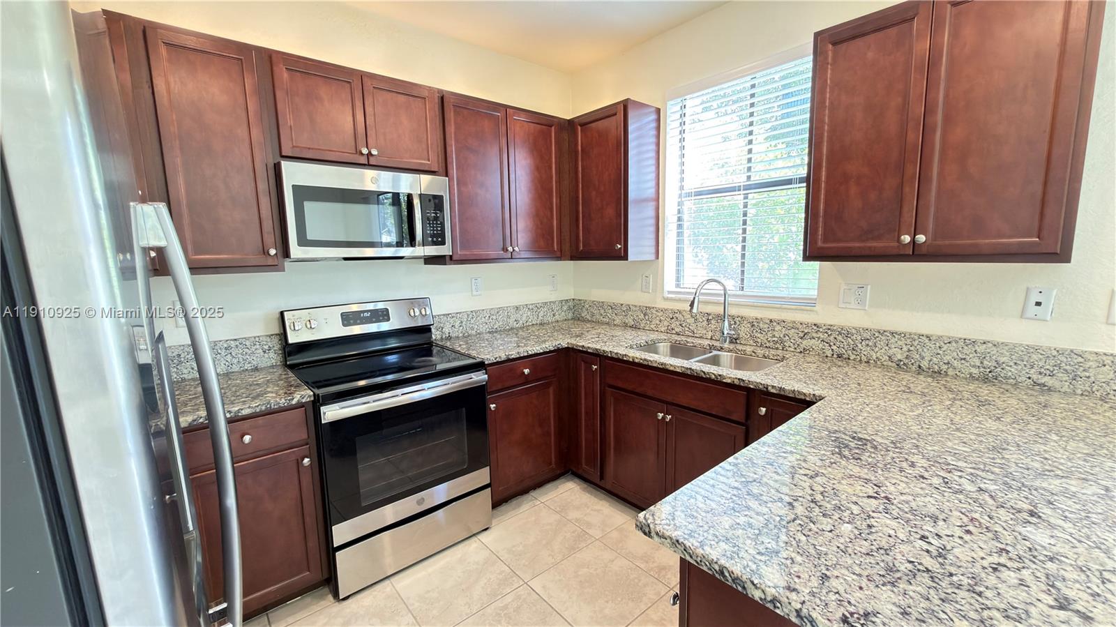 10337 West 34th Lane, Unit 10337 Hialeah, FL 33018 - Photo 16 of 50 a kitchen with stainless steel appliances granite countertop wooden cabinets a stove top oven a sink and dishwasher