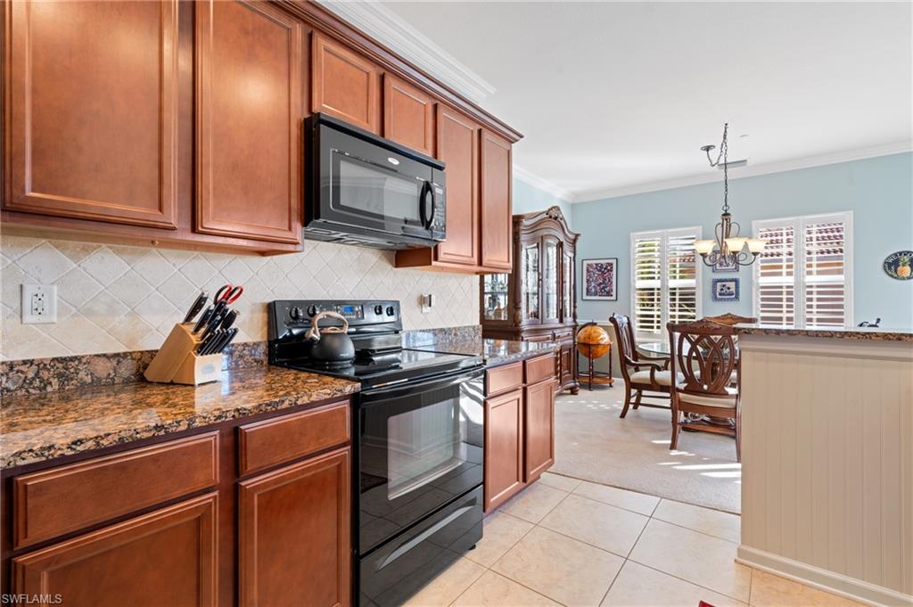 10057 Via Colomba Circle, Unit 206 Fort Myers, FL 33966 - Photo 23 of 46 a kitchen with stainless steel appliances granite countertop a stove top oven a sink a dining table and chairs with wooden floor