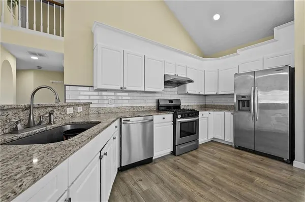 a kitchen with stainless steel appliances granite countertop a sink stove and refrigerator