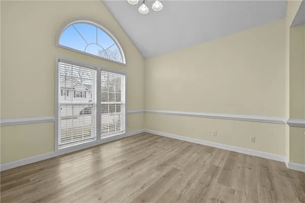 an empty room with wooden floor cabinet and windows