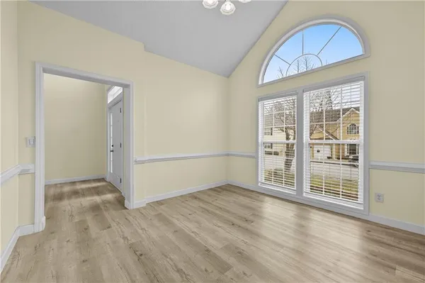 an empty room with wooden floor cabinet and windows