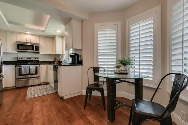 a kitchen with stainless steel appliances a table chairs in it and wooden floors