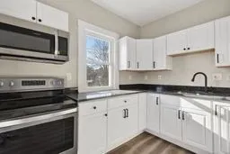 a kitchen with granite countertop white cabinets and stainless steel appliances