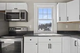 a kitchen with stainless steel appliances granite countertop white cabinets and a stove a oven with white countertops