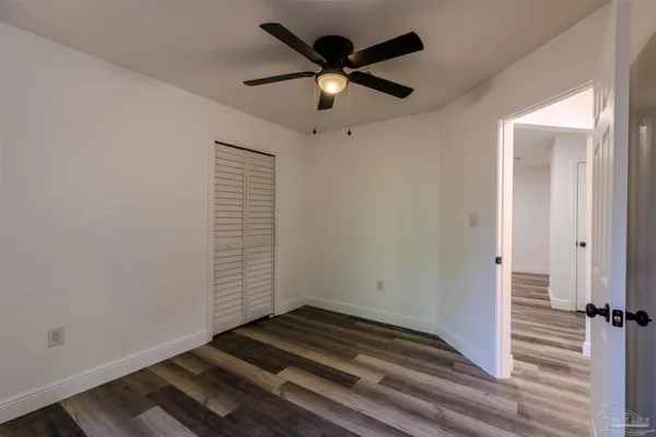 an empty room with wooden floor cabinet and windows