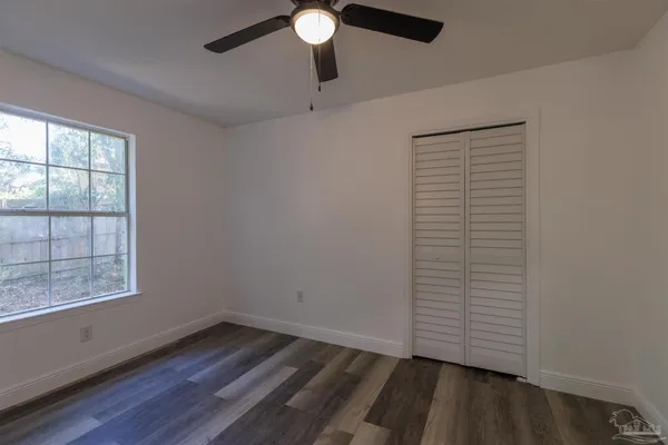 an empty room with wooden floor cabinet and windows