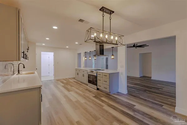 a kitchen with stainless steel appliances kitchen island granite countertop a sink and dishwasher a stove with wooden floor