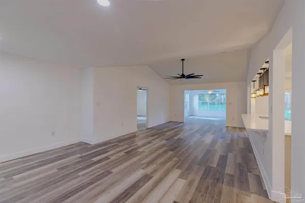 a view of a room with wooden floor ceiling fan and window