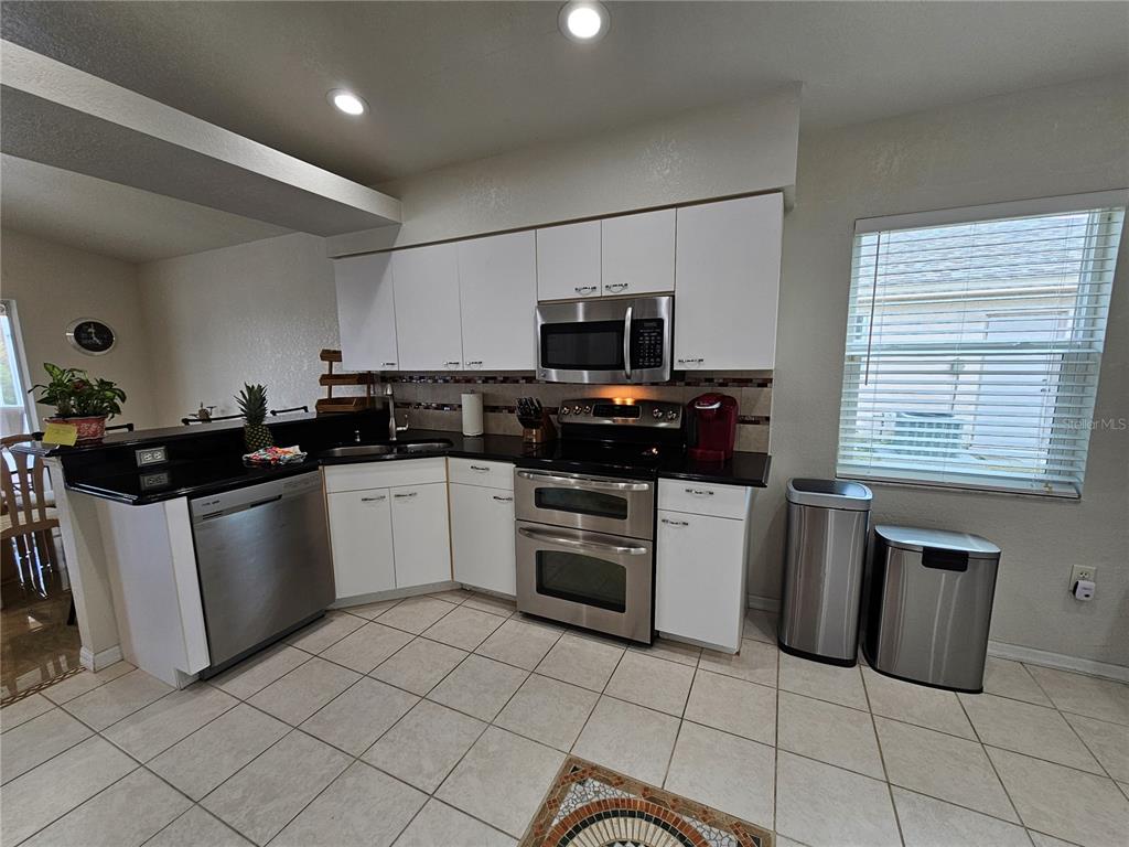 114 Albatross Road Rotonda West, FL 33947 - Photo 11 of 36 a kitchen with a sink a stove top oven and white cabinets