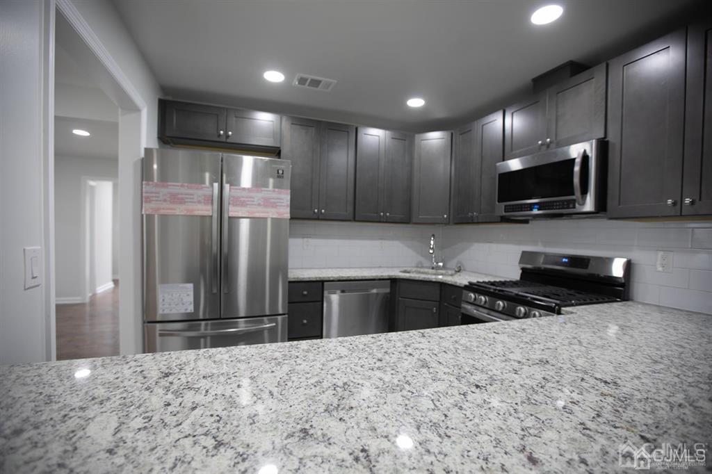 4208 Hana Road Edison, NJ 08817 - Photo 19 of 34 a kitchen with granite countertop a refrigerator and a stove top oven