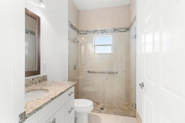 a bathroom with a granite countertop sink a toilet and shower