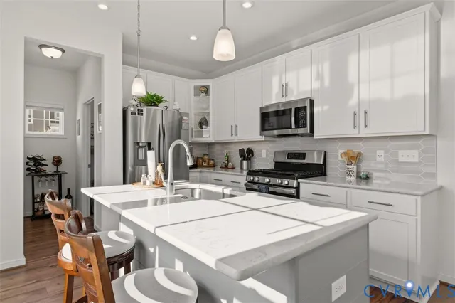 a kitchen with stainless steel appliances granite countertop a refrigerator a stove a sink and white cabinets