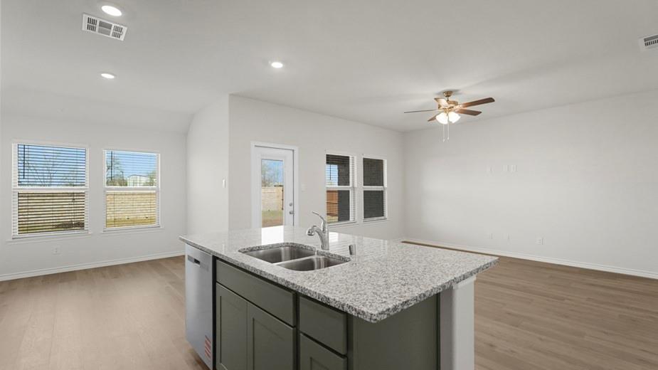 439 Epiphany Lane Lavon, TX 75166 - Photo 3 of 31 Kitchen island with integrated double basin sink, granite countertop, and dark cabinetry