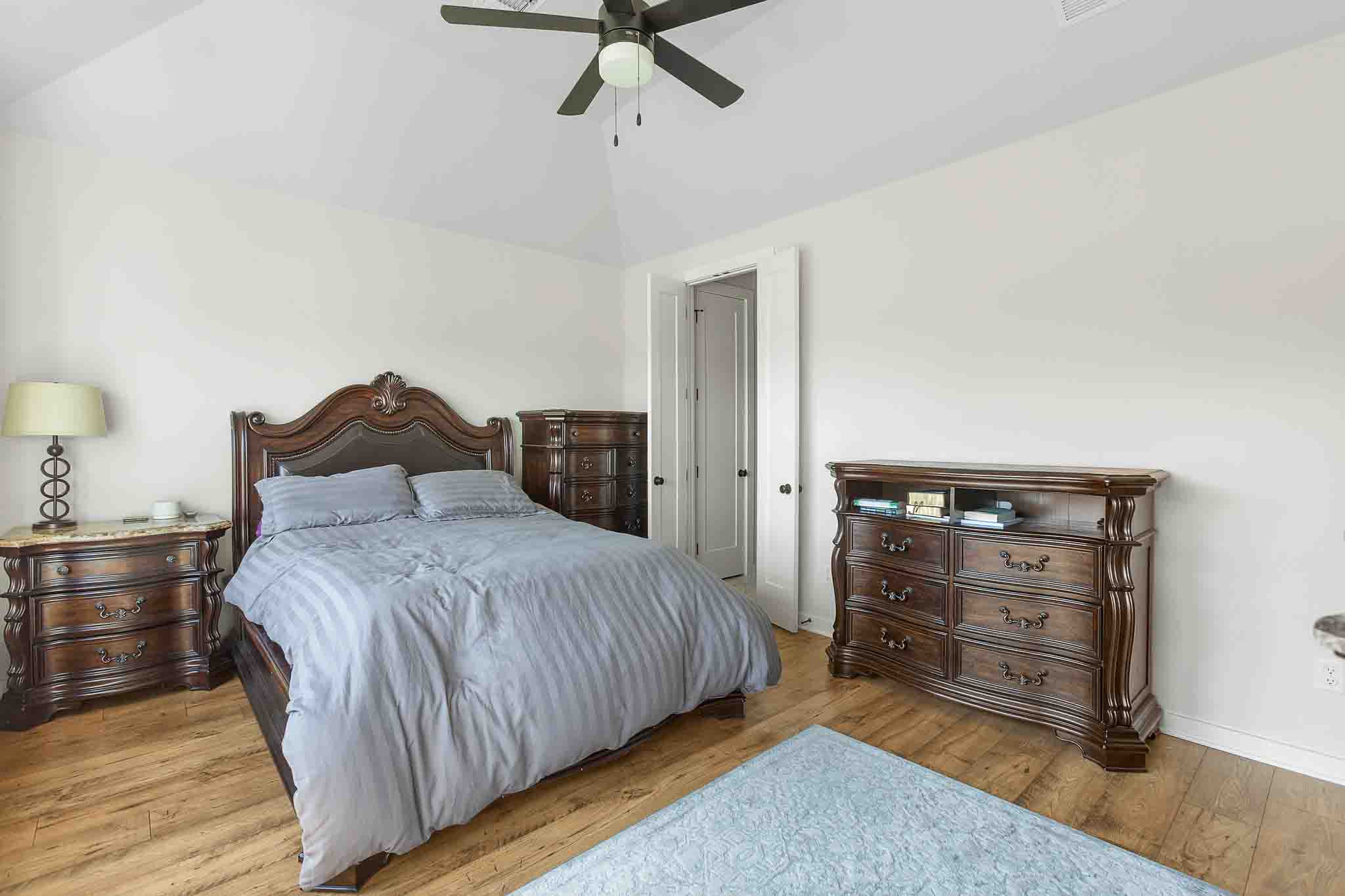 220 Basket Flower Loop Kyle, TX 78640 - Photo 15 of 40 Hardwood floors and a vaulted ceiling complement this naturally lit and comfortable sleeping space.