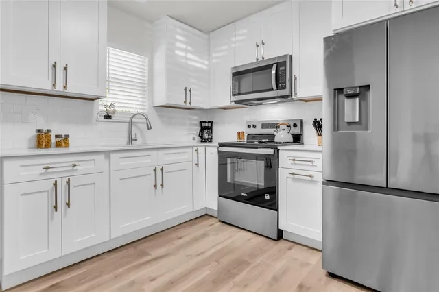 a kitchen with cabinets stainless steel appliances a sink and wooden floor