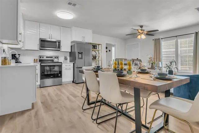 a kitchen with stainless steel appliances a table chairs refrigerator and cabinets