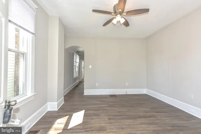 a view of empty room with wooden floor and fan