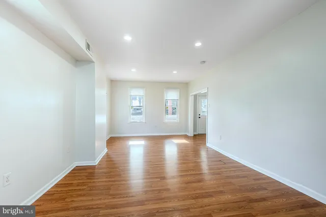 a view of an empty room with wooden floor and window