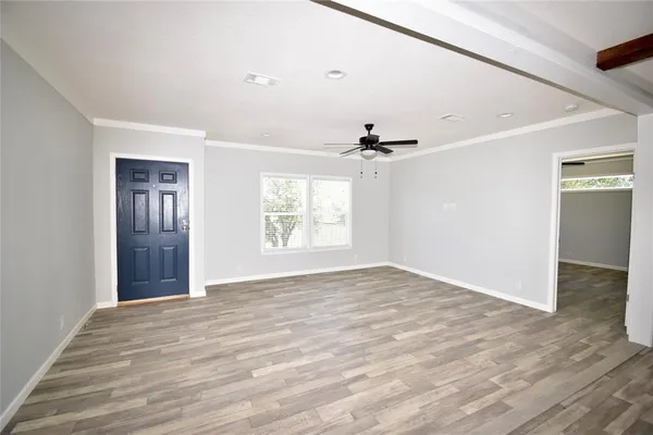 a view of an empty room with wooden floor and a window
