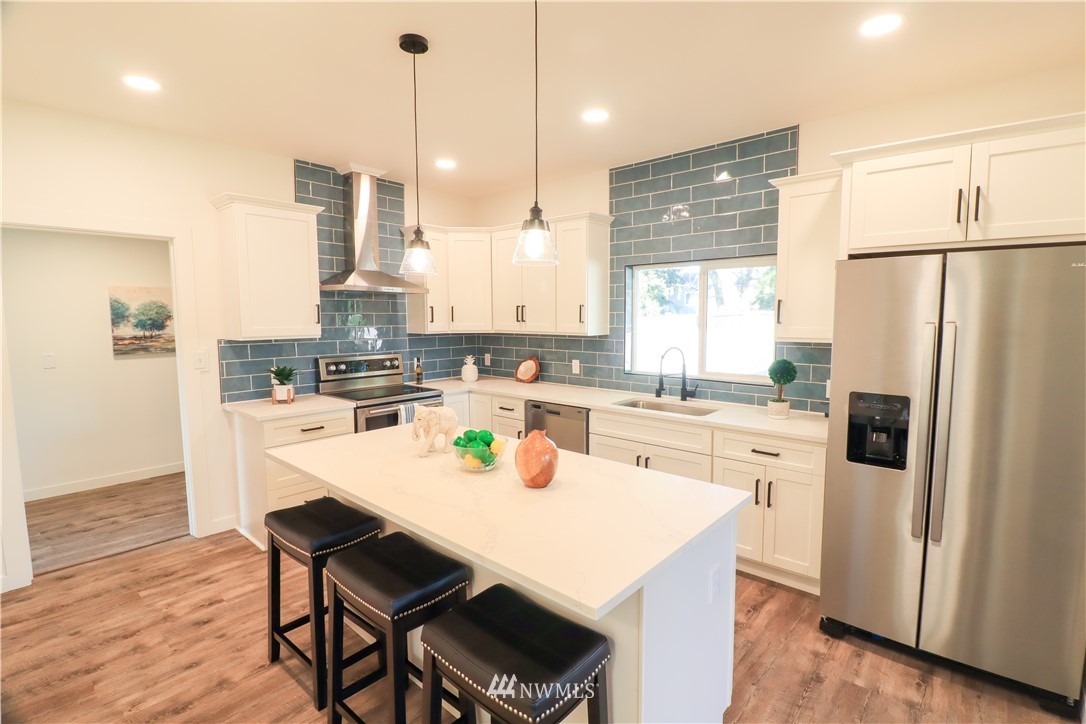 9331 Cullens Road Southeast Yelm, WA 98597 - Photo 11 of 28 a kitchen with a sink a refrigerator and white cabinets with wooden floor