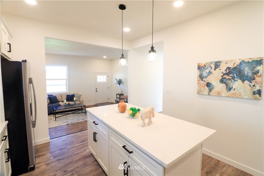 9331 Cullens Road Southeast Yelm, WA 98597 - Photo 12 of 28 a large white kitchen with a stove a sink a refrigerator and a dining table with wooden floor