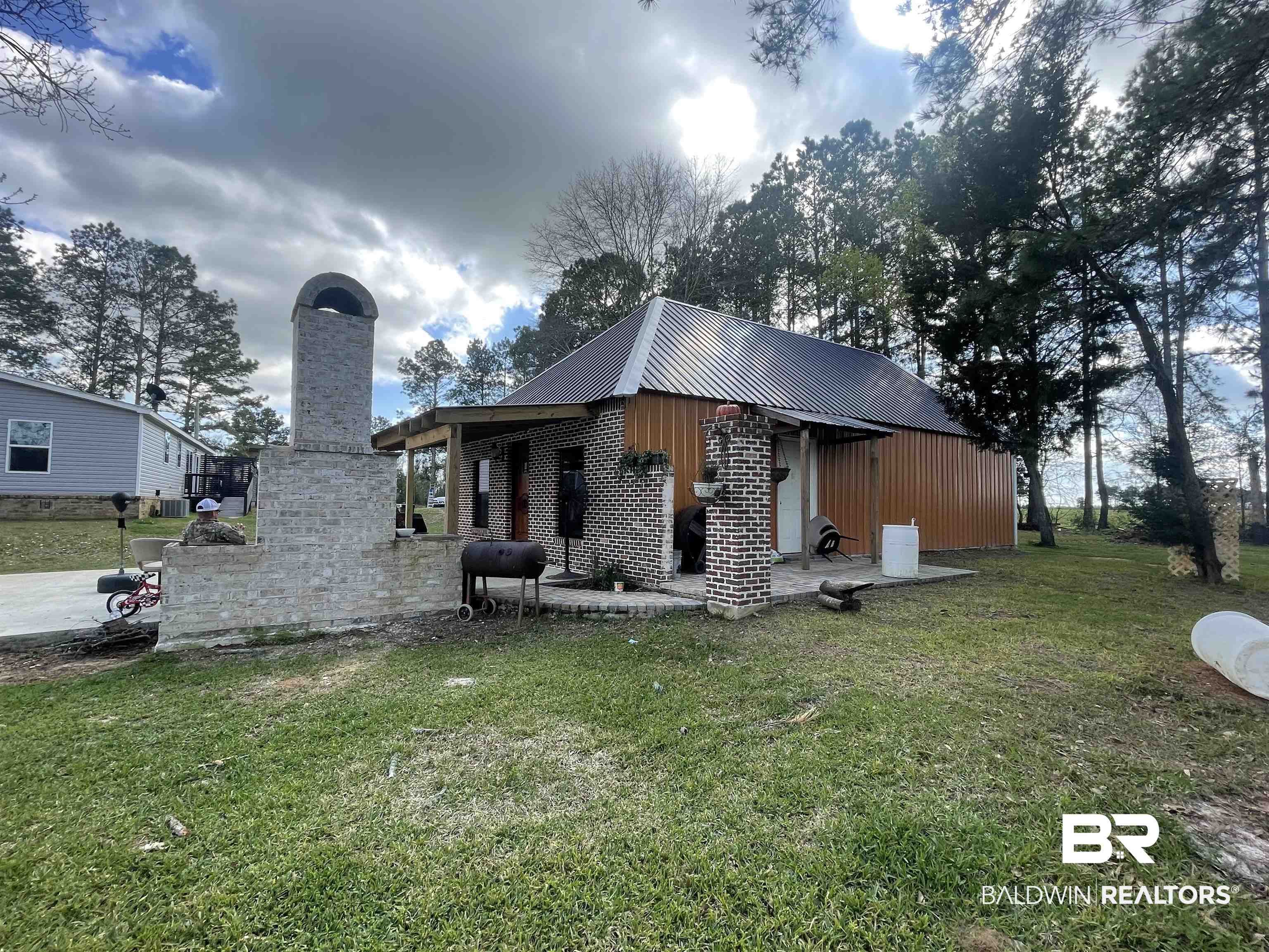 21593 Hubbard Road Robertsdale, AL 36567 - Photo 21 of 22 Rear view of house featuring a lawn, a chimney, and metal roof