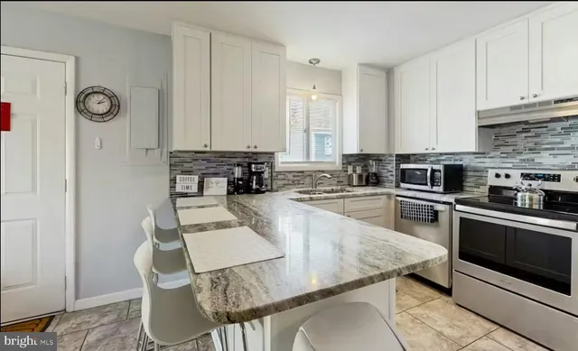 a kitchen with granite countertop a stove a sink and a refrigerator