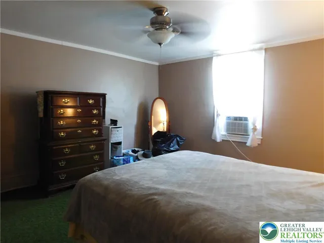a bedroom with a bed and a flat tv screen on dresser