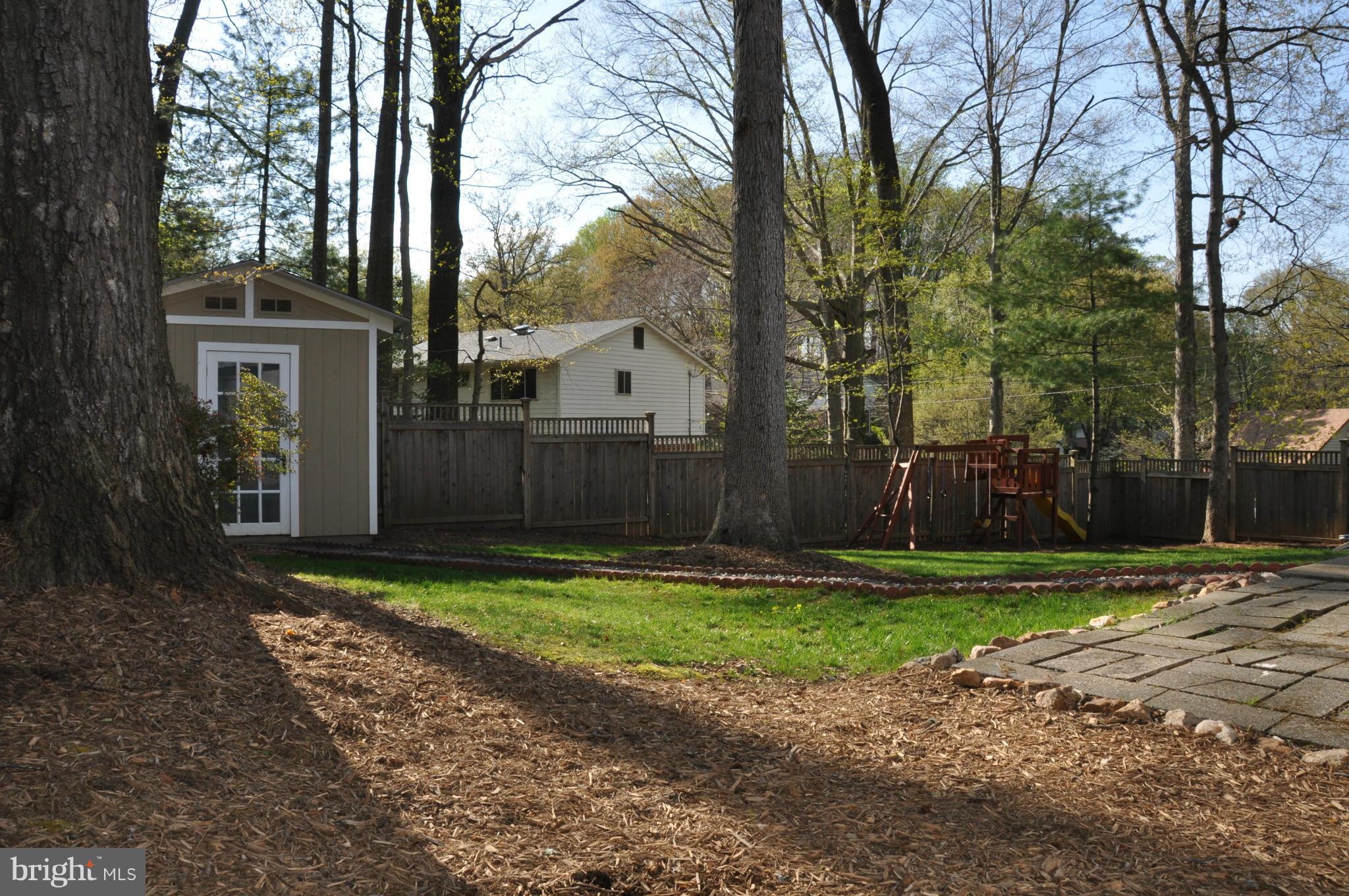 8621 Victoria Road Springfield, VA 22151 - Photo 25 of 27 a view of a backyard with large trees and wooden fence