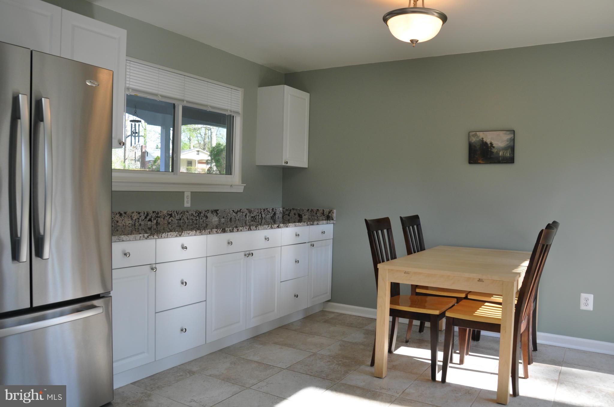 8621 Victoria Road Springfield, VA 22151 - Photo 6 of 27 a kitchen with granite countertop a sink cabinets a refrigerator a stove a dining table and chairs