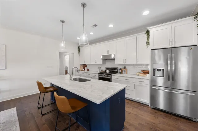 a kitchen with stainless steel appliances granite countertop a stove a refrigerator and a white cabinets