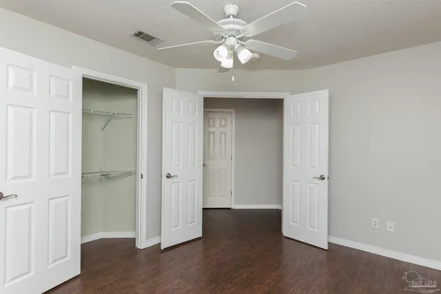 an empty room with wooden floor and ceiling fan