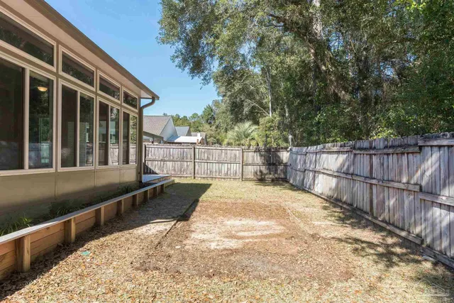 a view of backyard with wooden fence and large trees