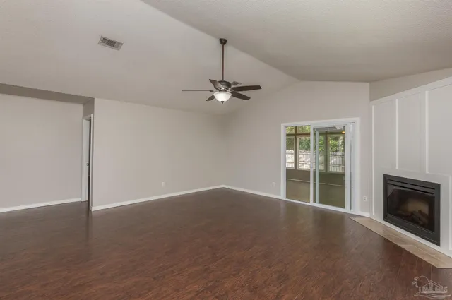 a view of a livingroom with wooden floor a ceiling fan and a window
