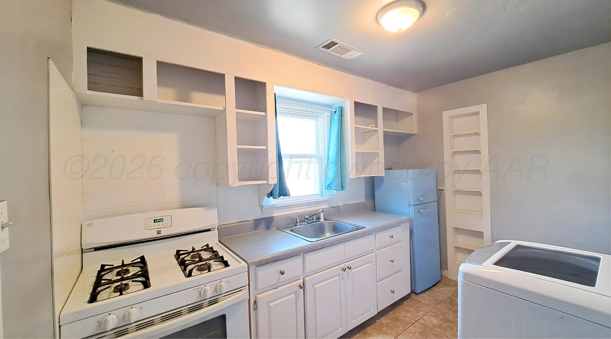 118 South Austin Street Amarillo, TX 79106 - Photo 5 of 9 a kitchen with white cabinets and white appliances