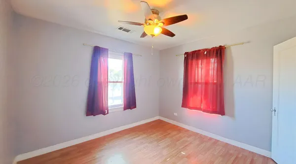 a view of an empty room with window and a chandelier fan