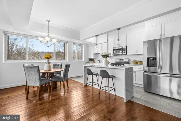 a kitchen with stainless steel appliances a dining table chairs stove refrigerator and cabinets