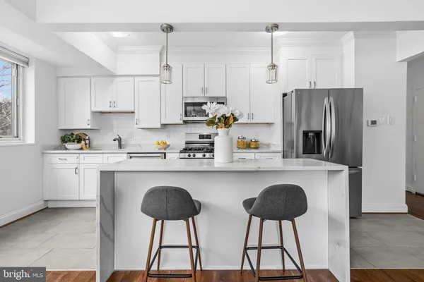 a kitchen with stainless steel appliances a refrigerator a stove a sink and white cabinets