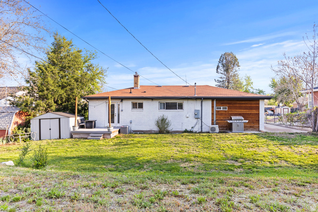 2101 West 3900th Street South Roy, UT 84067 - Photo 6 of 36 Expansive lawn with a white exterior structure featuring a brown shingle roof, chimney, and a rear deck