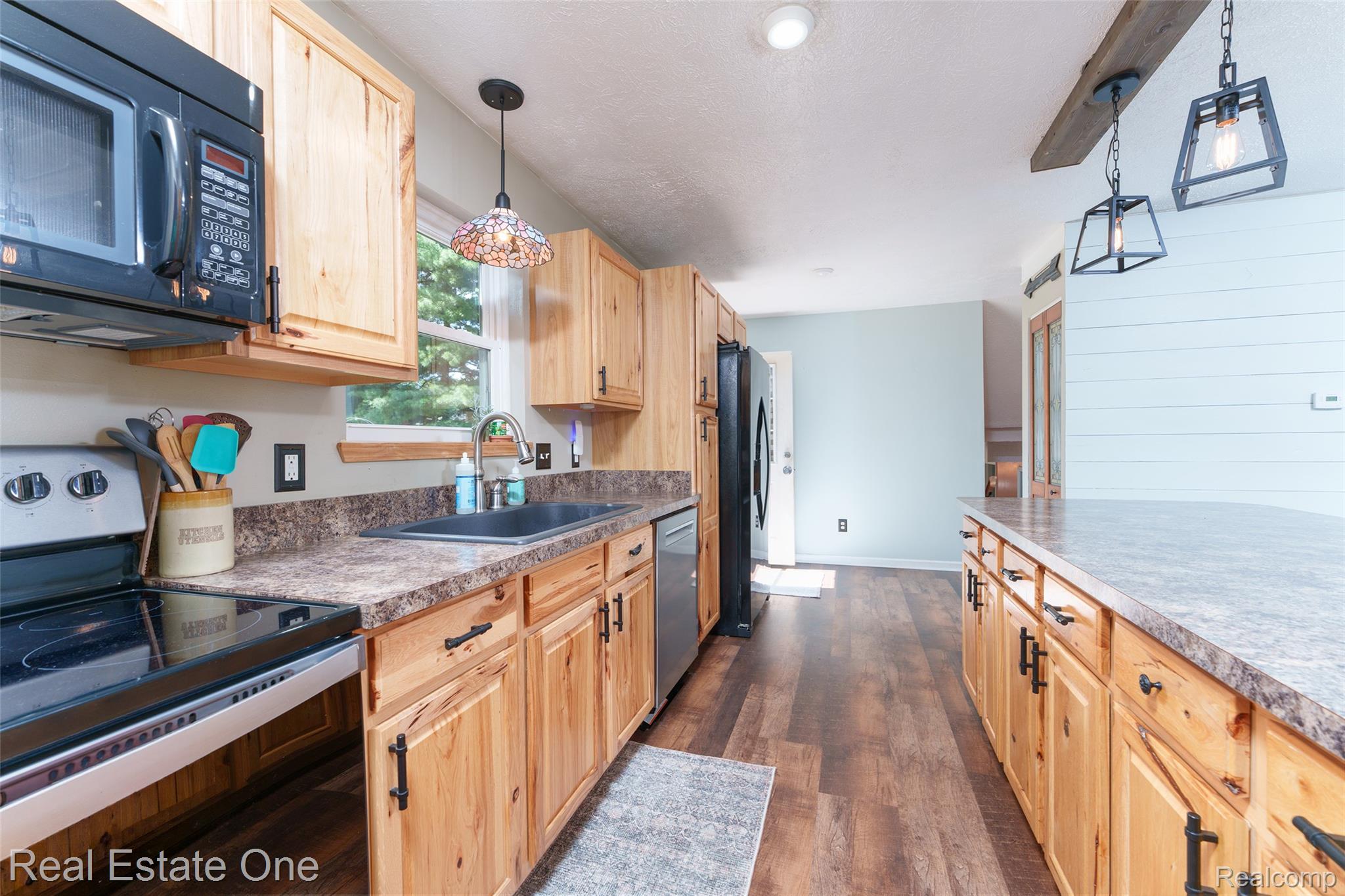 5130 Iosco Road Webberville, MI 48892 - Photo 20 of 39 Kitchen featuring wood cabinetry, dark countertops, wood-finish flooring, recessed lighting, and an island with pendant lighting