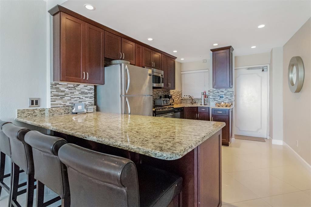 710 North Ocean Boulevard, Unit 806 Pompano Beach, FL 33062 - Photo 5 of 19 a kitchen with stainless steel appliances granite countertop a sink refrigerator and cabinets