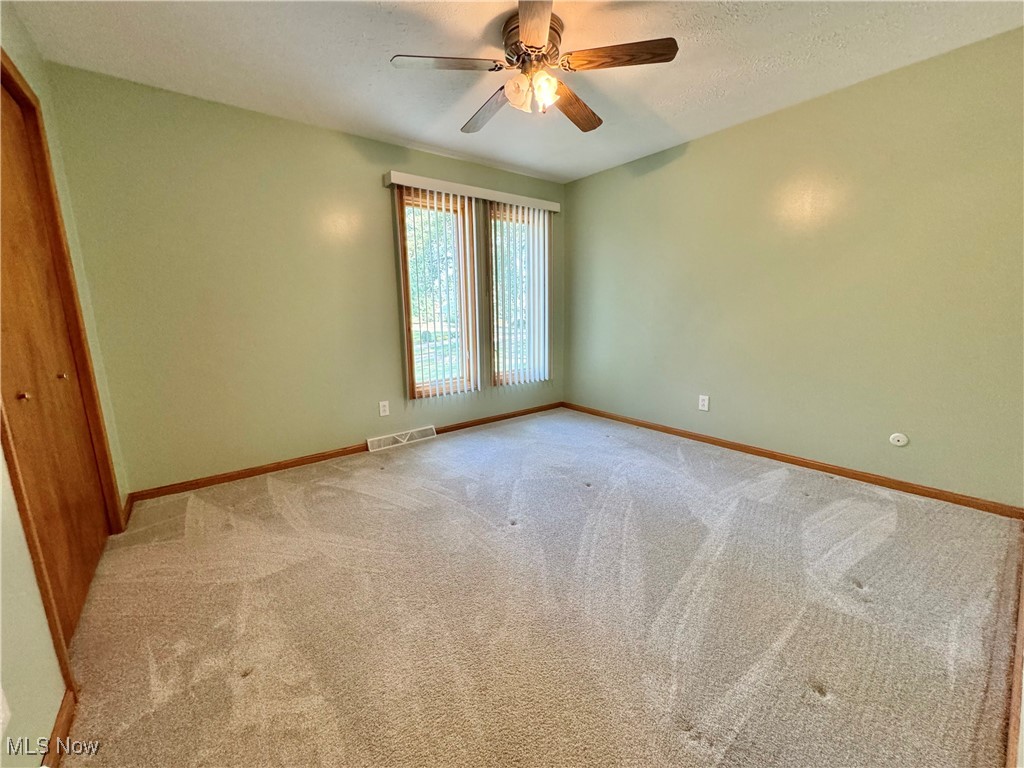 2180 Portage Line Road Uniontown, OH 44685 - Photo 17 of 25 Empty room featuring ceiling fan, light carpet, and a textured ceiling