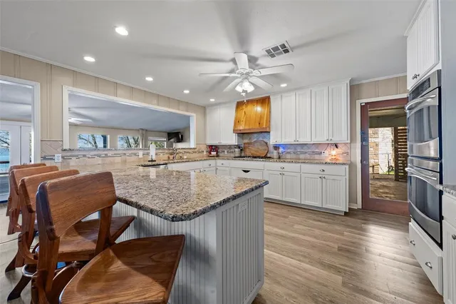 a kitchen with stainless steel appliances granite countertop a sink a stove and a wooden floors