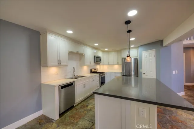 a kitchen with stainless steel appliances granite countertop a sink refrigerator and cabinets